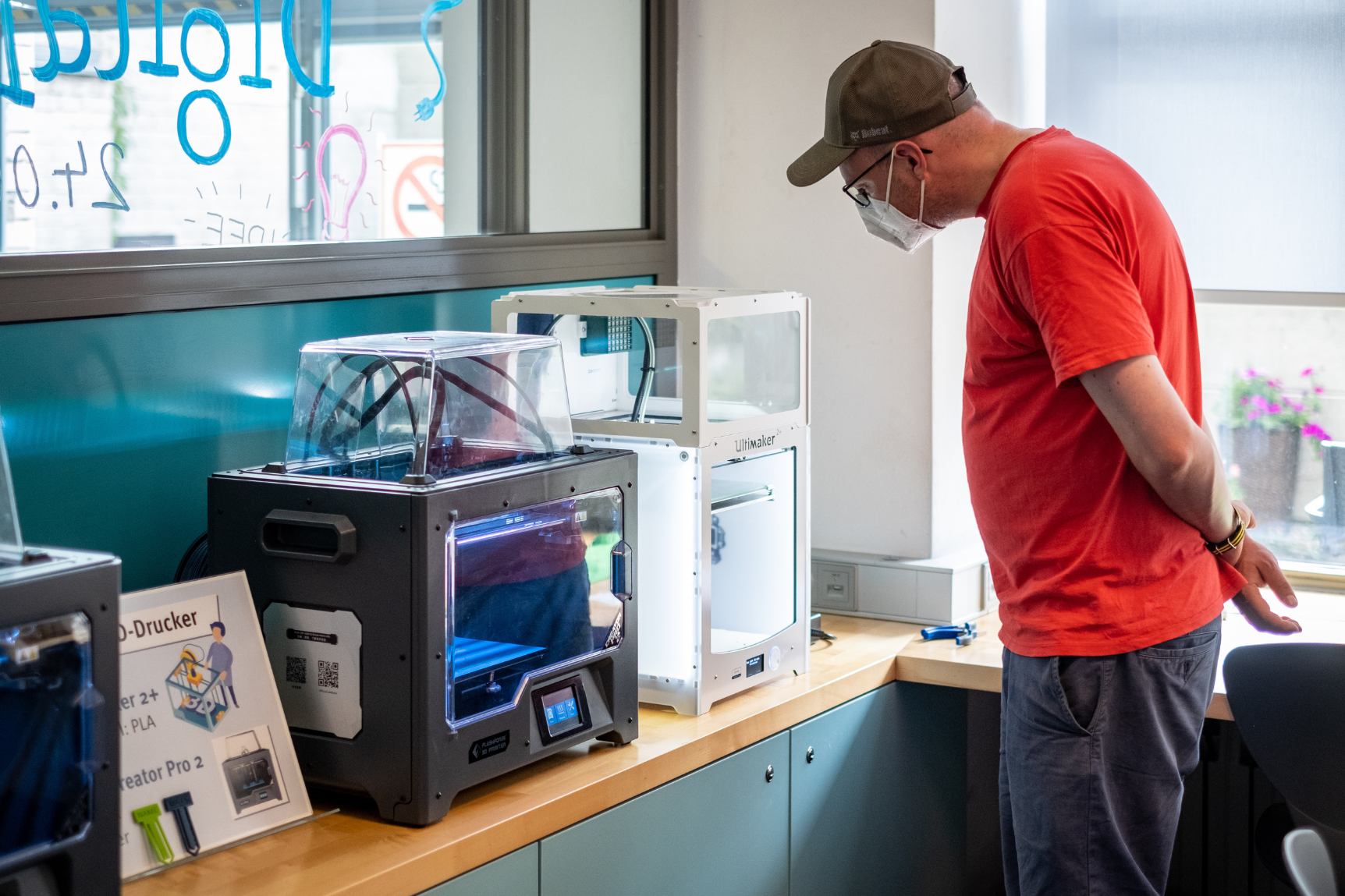 Ein Mann schaut sich einen 3D-Drucker an
