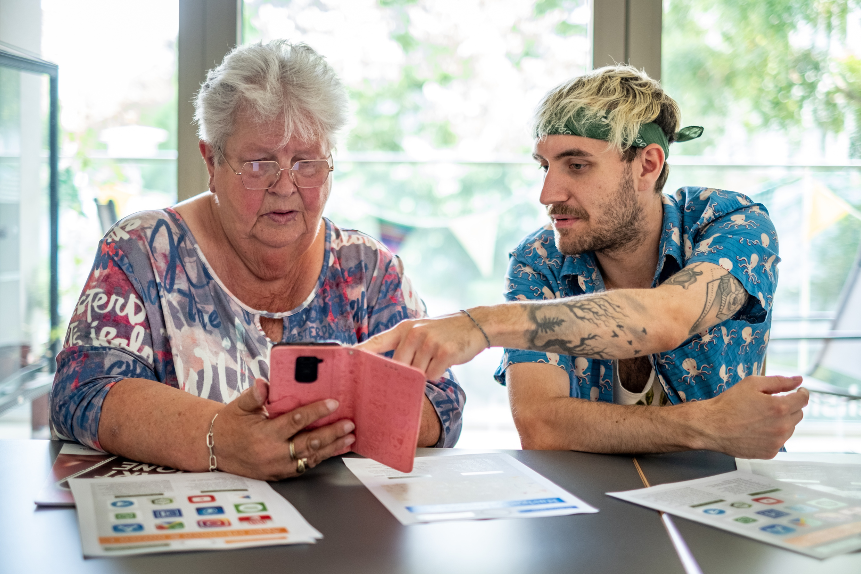 Ein junger Mann hilft einer älteren Dame mit ihrem Smartphone