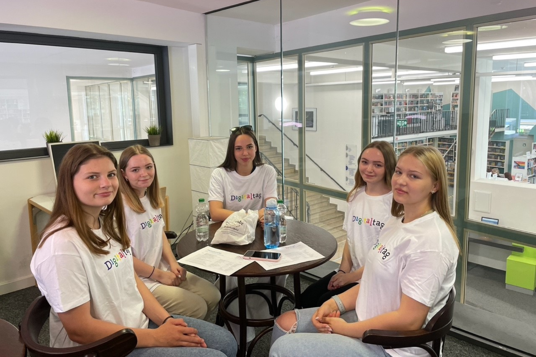 Fünf Schülerinnen mit Digitaltag-T-Shirts, die bei einer Smartphone-Sprechstunde helfen