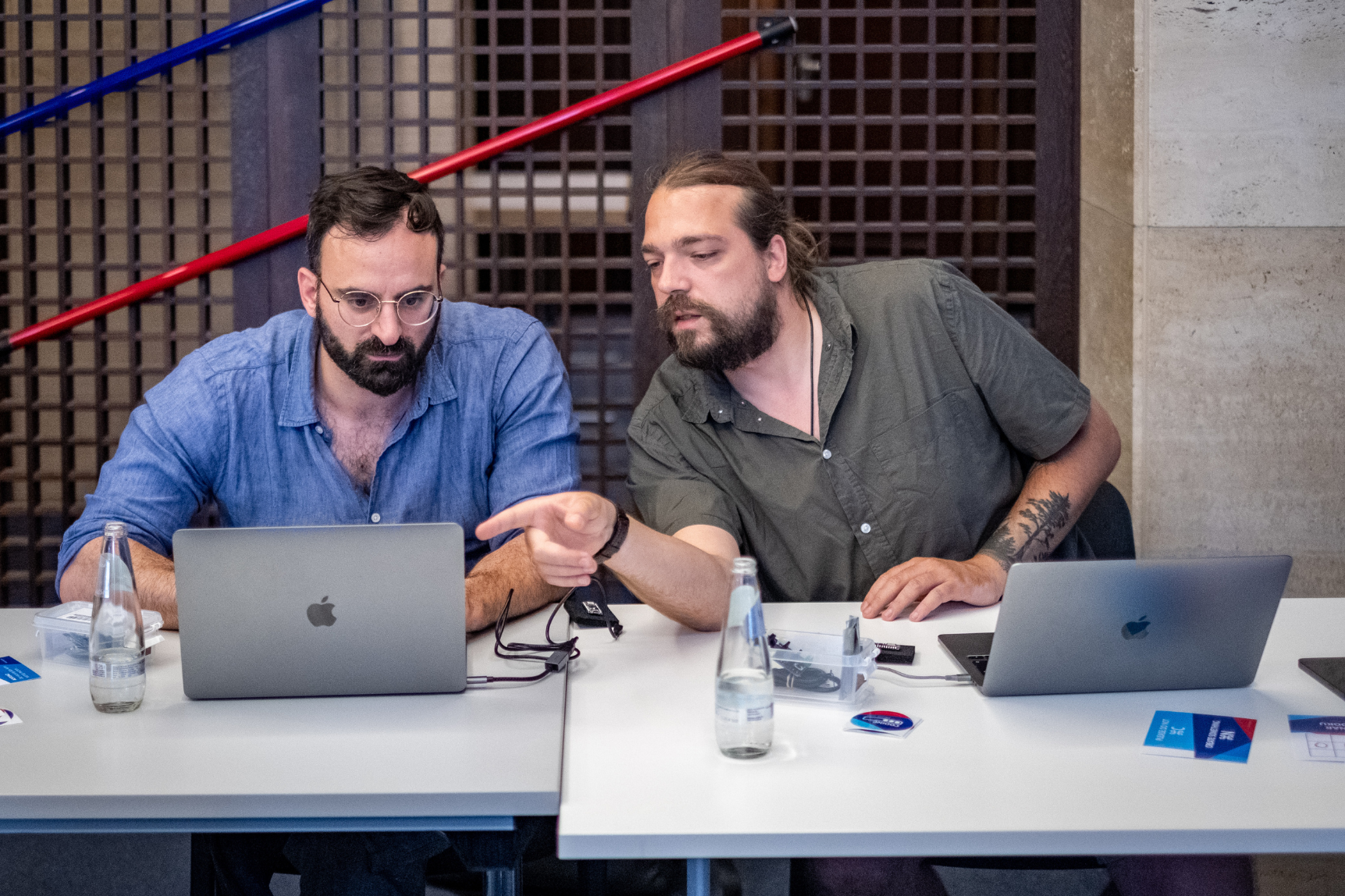 Zwei Männer sitzen vor ihren Laptops und unterhalten sich