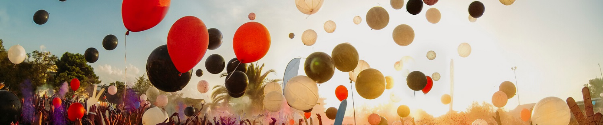 Menschenmenge feiert und lässt bunte Luftballons in den Himmel aufsteigen
