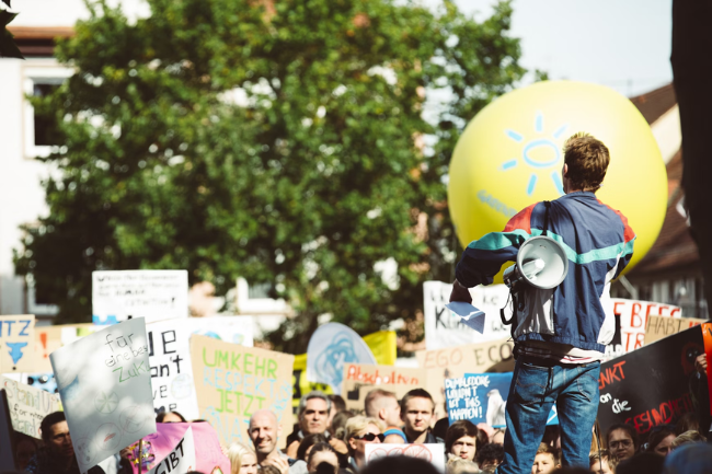 Menschen draußen bei einer Demo, die Pappschilder hochhalten