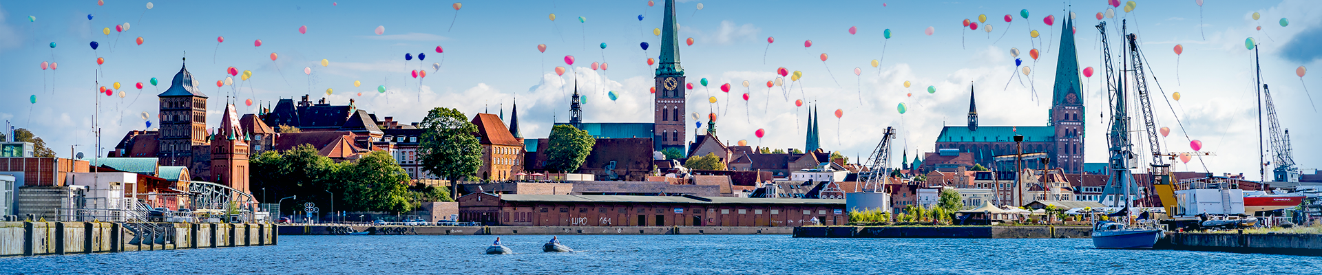 Ansicht der Stadt Lübeck vom Wasser aus, bunte Luftballons steigen in den Himmel