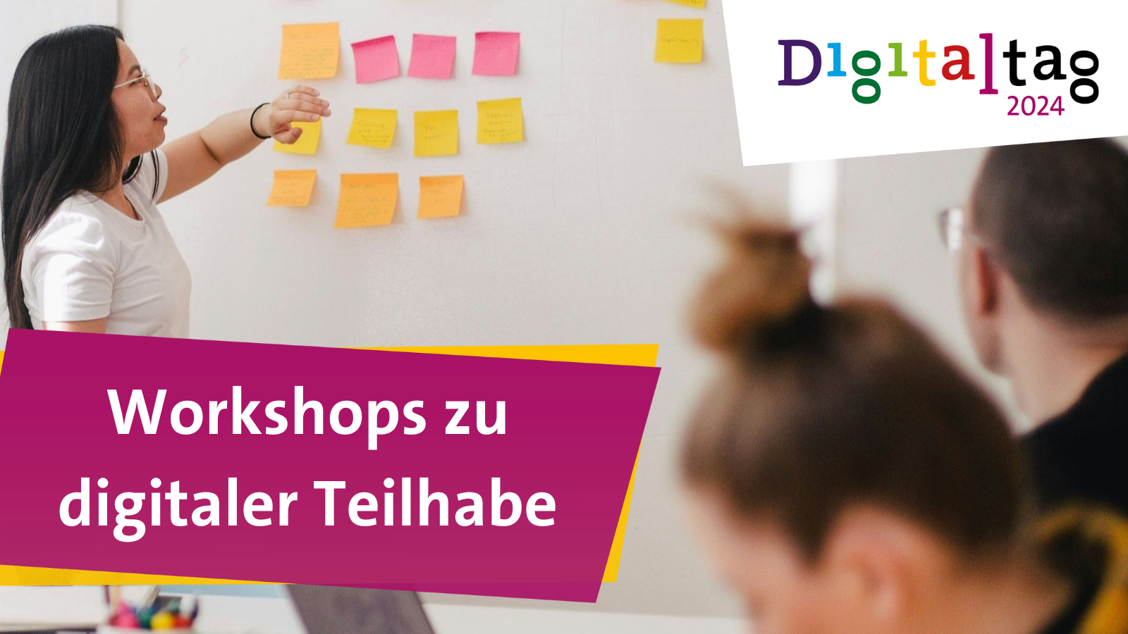 Das Bild zeigt einen Workshop, bei dem eine Person mit dem Rücken zur Kamera auf Haftnotizen an einer Wand zeigt und mehrere andere Personen ihr gegenüber sitzen, die am Workshop teilnehmen. In der oberen rechten Ecke befindet sich ein Logo mit dem Text “Digitaltag 2024”. Darunter befindet sich ein magentafarbener Banner mit dem Text “Workshops zu digitaler Teilhabe”.
