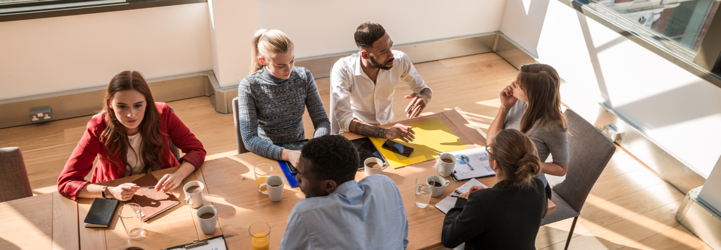 Teilnehmende eines Workshops sitzen an einem Tisch und diskutieren miteinander. 
