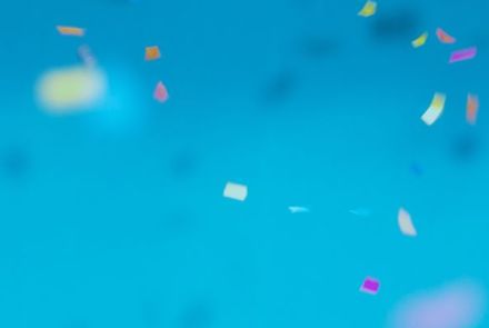 Buntes Konfetti fällt vor türkisem Hintergrund