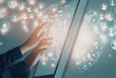 Eine Person bedient einen großen digitalen Bildschirm. Im Hintergrund sind vernetzte Symbole von Personen und eine leuchtende, kugelförmige Netzwerkstruktur zu sehen, die digitale Kommunikation, Vernetzung und Zusammenarbeit symbolisieren.