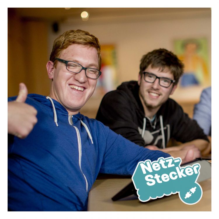 Zwei junge Männer mit Brille, einer zeigt ein Daumen hoch, unten rechts das Netz-Stecker-Logo