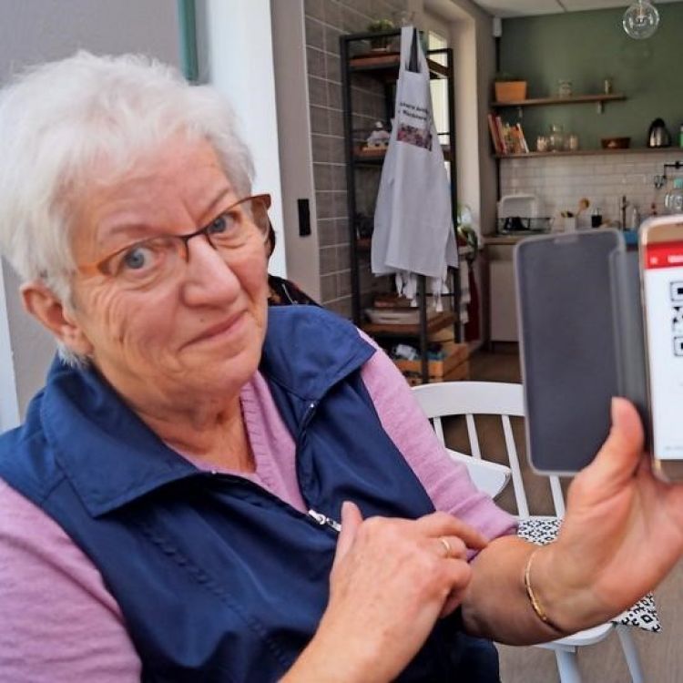 Seniorin zeigt Handy in die Kamera