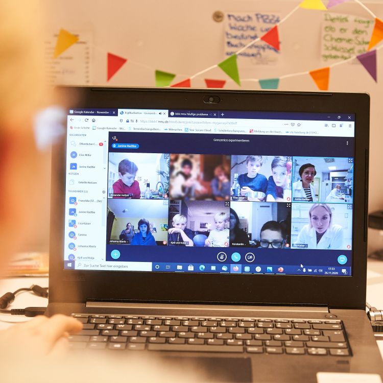 Laptopbildschirm zeigt Zoom-Kacheln verschiedener Kinder, die online zusammen experimentieren
