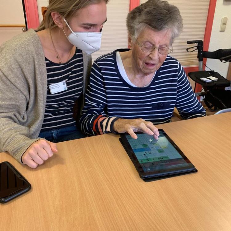 Rechts oben Logo des Digitaltags und blauer Fächer mit der Aufschrift "Publikumspreis 2022". Foto: Eine jüngere Frau hilft einer älteren Dame bei der Bedienung eines Tablets. Text: 2. Platz "Digitale Teilhabe", Miteinander Digital, Christophorus Pflege und Wohnen