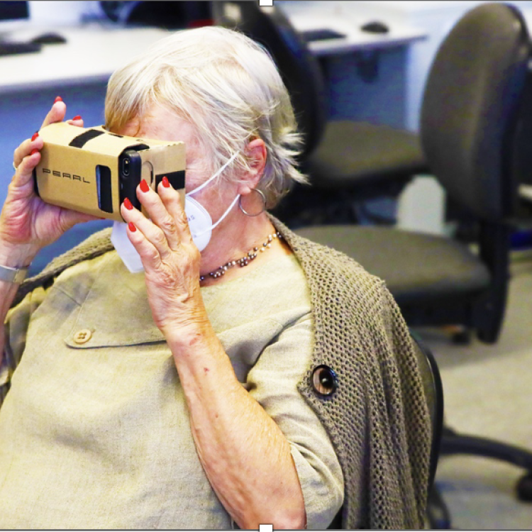 Eine ältere Frau mit Maske trägt eine VR-Brille