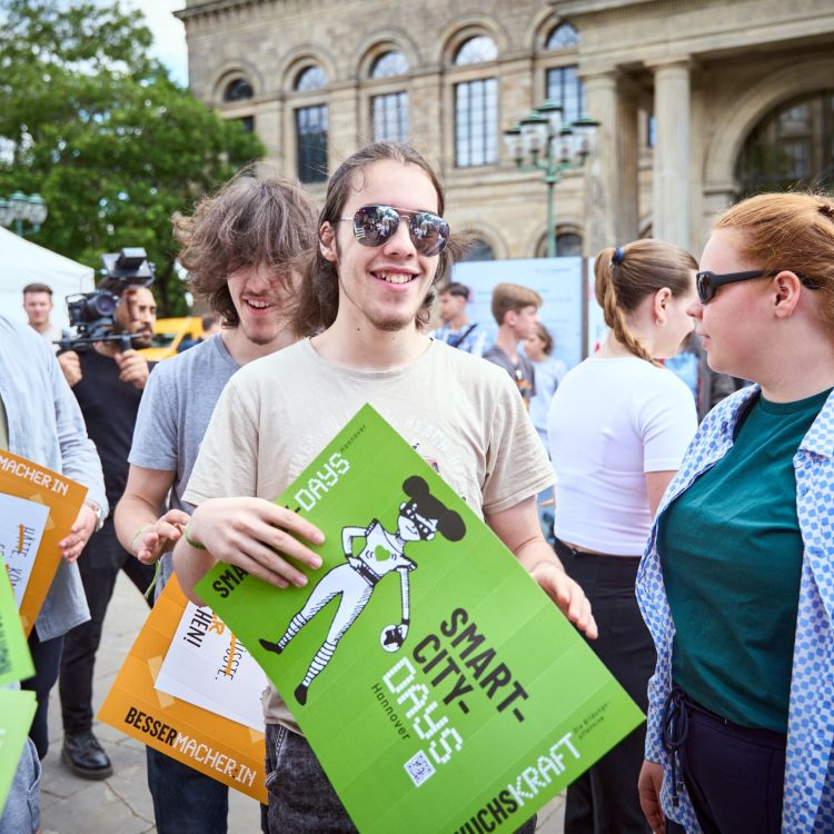 Bild einer jungen Menschengruppe draußen mit Schildern