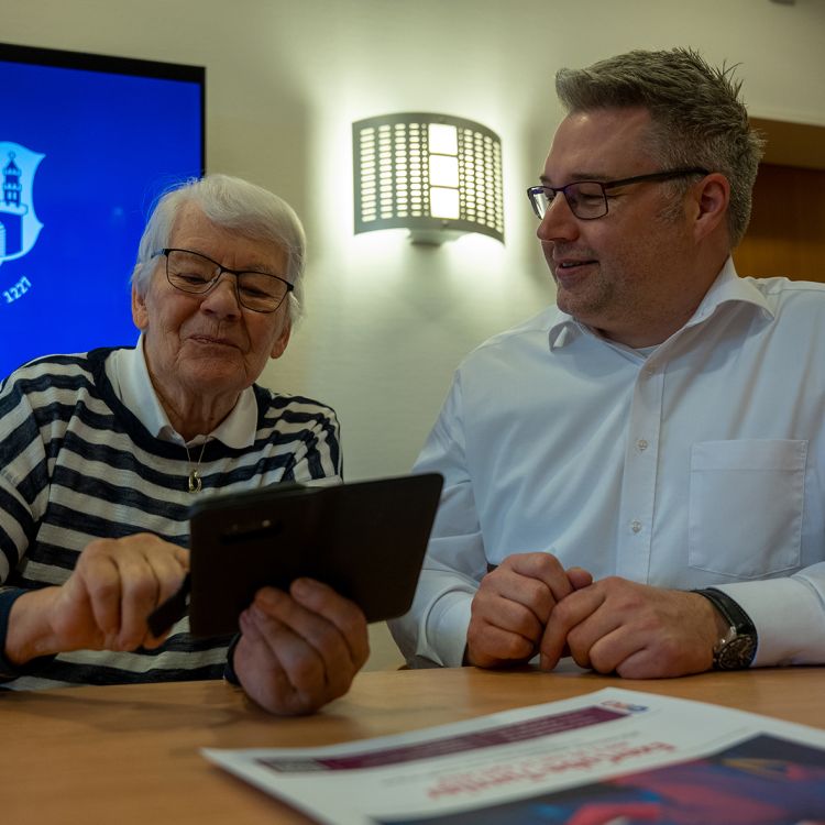 Ein Mann hilft einer älteren Frau bei der Bedienung ihres Smartphones
