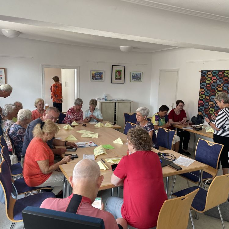 Eine Gruppe Seniorinnen und Senioren sitz um einen großen Tisch herum.