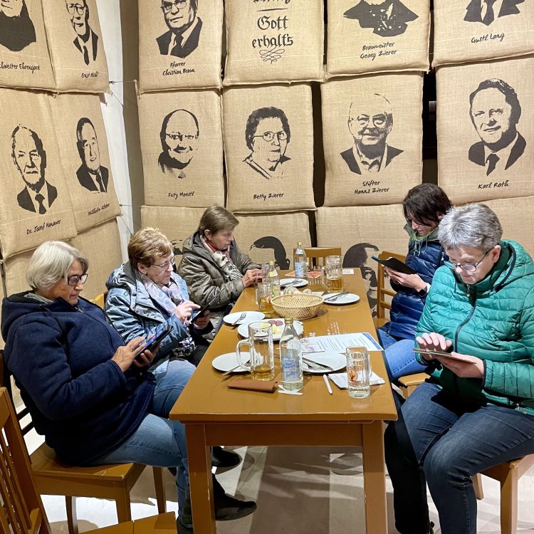 Eine Gruppe älterer Frauen sitzt an einem Tisch und experimentieren mit ihren Smartphones.