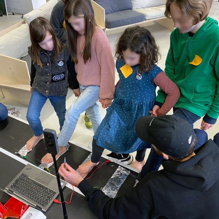 Eine Gruppe probiert mit ihren Füßen ein digitales Musikinstrument aus.