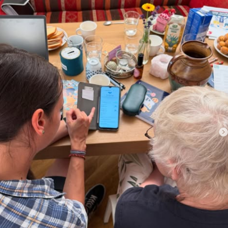 Eine Frau hilft einer älteren Frau bei der Bedienung ihres Smartphones.