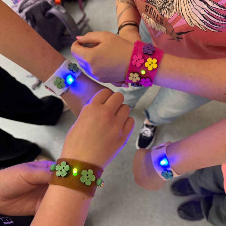 Eine Gruppe Kinder hält ihre leuchtenden Armbänder in Kamera